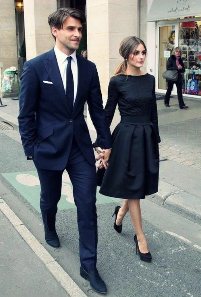 sharply dressed couple walking hand in hand, dark blue suit, white shirt and black tie, black retro midi dress, with long sleeves, black tie attire for men