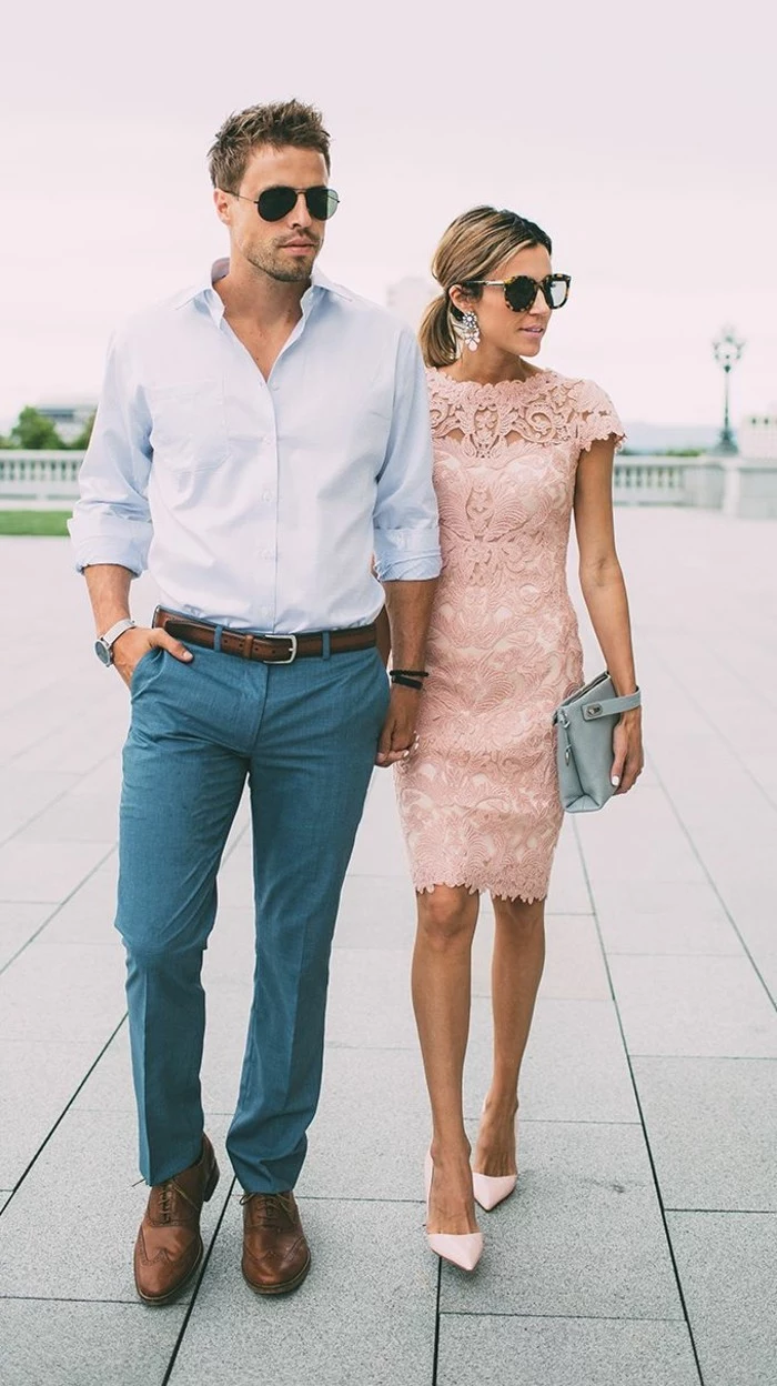 woman in pale pink, midi lace dress, walking hand in hand, with a young man, in pale blue shirt, and blue trousers, mens casual summer wedding attire, brown brogue shoes