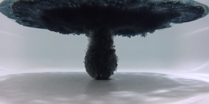 underwater image showing a black bath bomb, dissolving into a white bathtub, filled with water