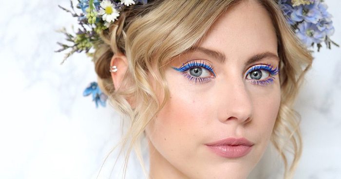 blue eyeliner worn by green-eyed woman, with nude pink lipstick, and soft blush, makeup looks, blonde hair tied up, and decorated with various flowers