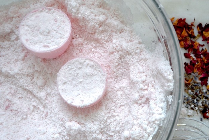 putting fine pale pink powder, inside a plastic easter egg, with two parts, bath bomb recipe, large clear glass bowl, dried flower petals