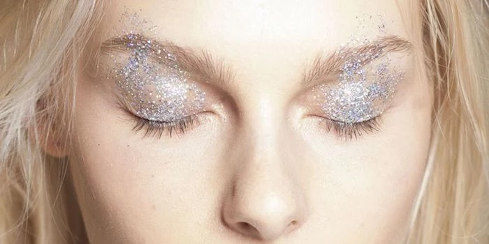 platinum blonde woman, with pale skin and closed eyes, wearing fine silver glitter, on her eyelids and eyebrows, make up ideas, 