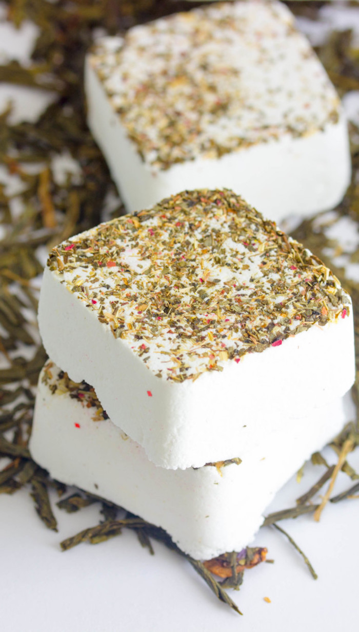 square white bath bomb tablets, in pure white, dusted with dried herbs, placed on white surface with more dried herbs