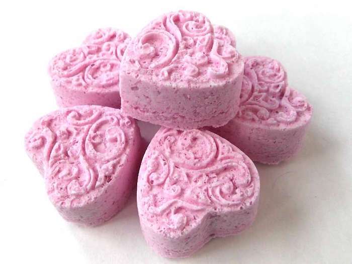 3D engraved pink bath bombs, six in total, shaped like hearts, what is a bath bomb, placed on white surface