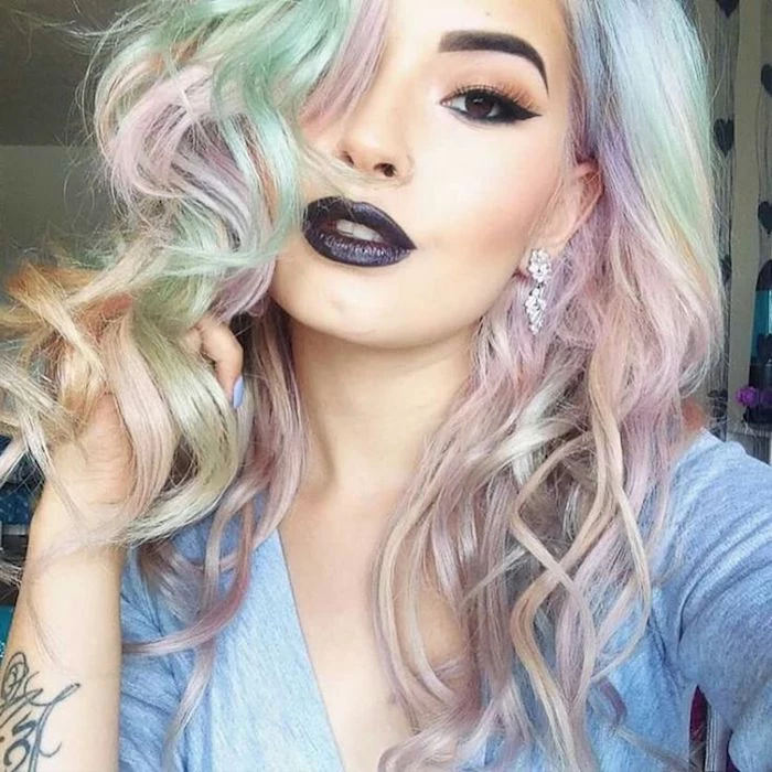pastel green pink and yellow hair, slightly curled and worn by young woman, with black lipstick, fake eyelashes, and black eyeliner