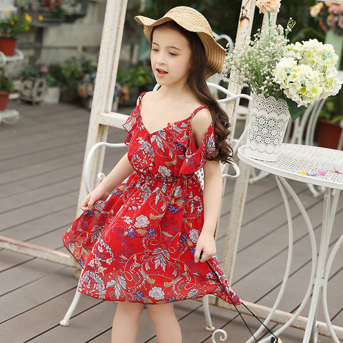 straw hat in pale beige, and floaty red sundress, with floral details and frills, worn by little girl, with long brunette hair