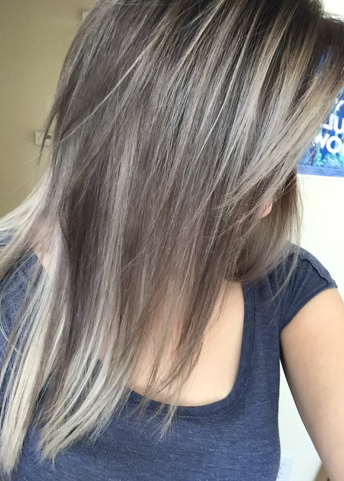 layered medium length hair, in mink brown, with light ash blonde streaks, light brown hair with blonde highlights, worn by young woman, in dark grey t-shirt