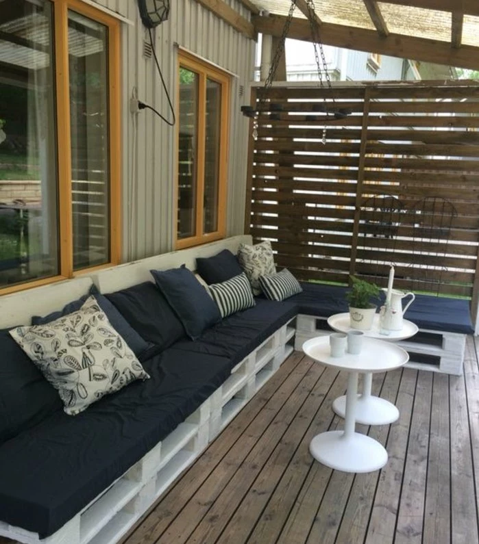 pallet outdoor furniture, terrace or porch bench, made from wooden pallets, painted in white, and covered with black foam pillows