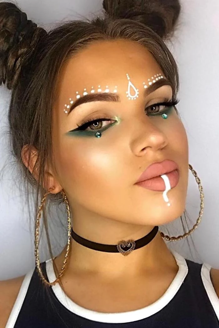 patterns done in white face paint, decorating the lips and forehead of a young girl, wearing turquoise eyeshadow, black eyeliner and nude pink matte lipstick