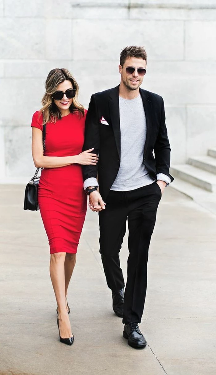 mens casual summer wedding attire, black suit and an off-white t-shirt, on young man with sunglasses, walking with a blonde woman, in a red midi dress