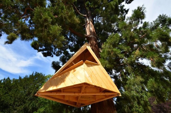 pyramid-shaped construction, made from pale wood, and suspended from a large fir tree, diy treehouse or shelter