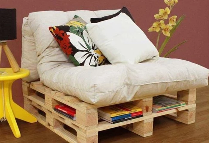 armchair made of wooden pallets, with storage space, furniture made from pallets, covered with large, soft pale beige pillows, and decorated with three cushions