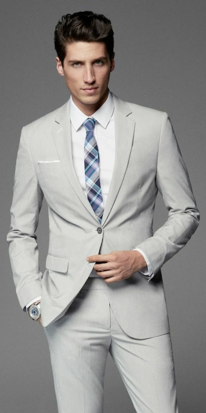 wristwatch and blue and white plaid tie, combined with a white shirt, and an off-white two piece suit, how to dress for a wedding male, young brunette man