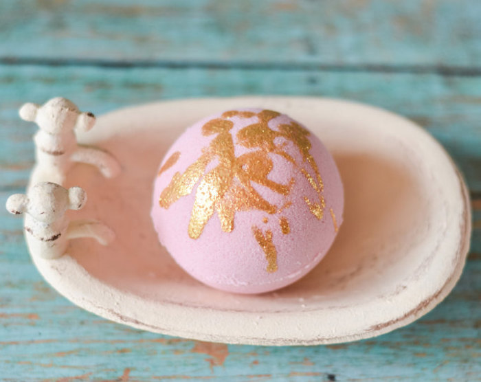 rose gold drizzle bath bomb, in light powdery pink, placed inside a pale pastel pink soap dish, bath fizzies recipes and ideas