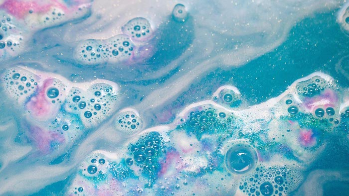 teal-colored water with white foam, how to make bath bombs, pink and purple tint, seen in extreme close up