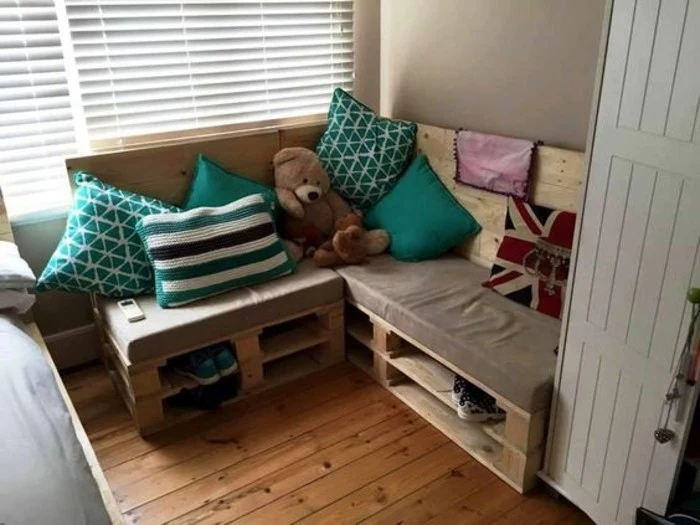 kids's room pallet couch, with a foam mattress, with a beige cover, decorated with several cushions, in turquoise and white, patterned and plain