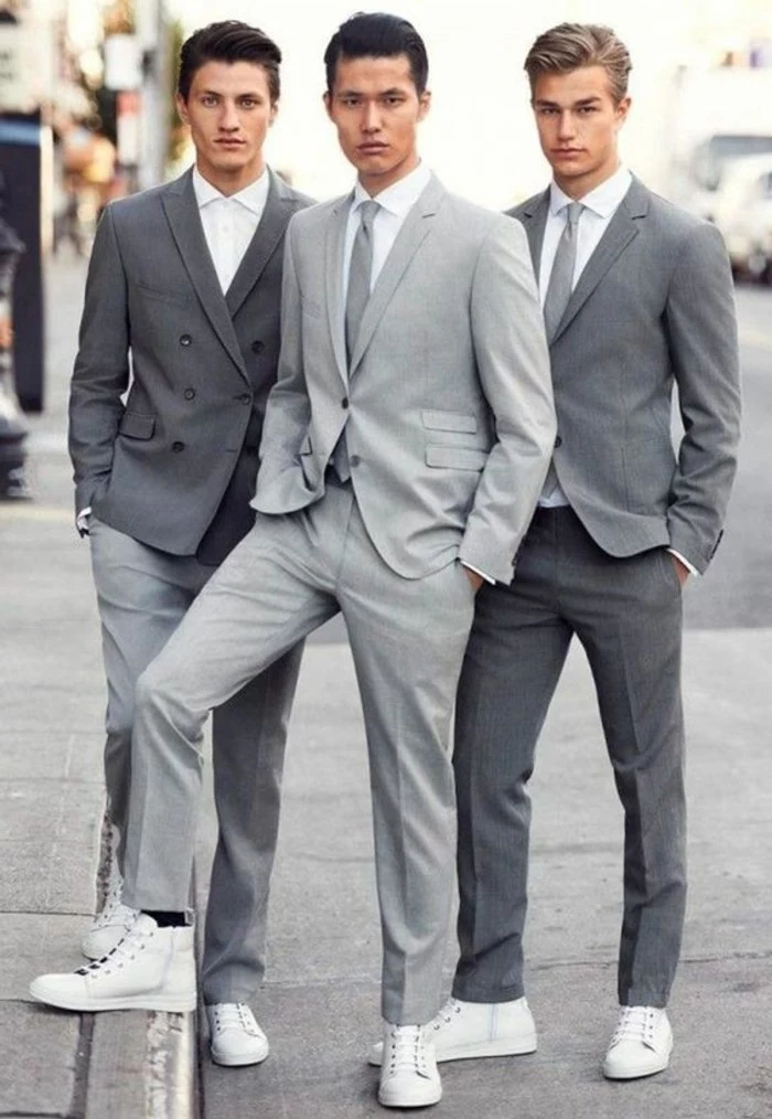 different shades of grey, worn by three young men, in smart two piece suits, all have white shirts and white sneakers, two of them are wearing ties