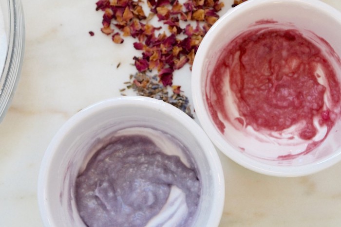 violet and pink creamy substance, inside two small white ceramic bowls, placed on marble surface, near dried lavender, and dark pink rose petals, bath bomb recipe