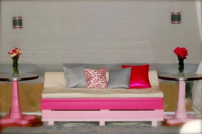 fuchsia and baby pink painted pallets, used to make a pallet couch, covered with soft light beige mattress, and several cushions
