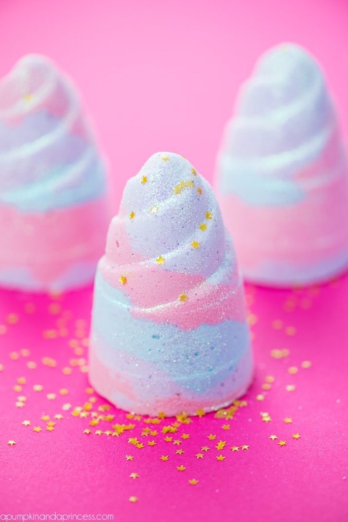 swirly pastel pale pink, blue and violet, homemade bath bombs, in unicorn-horn shape, decorated with golden star confetti