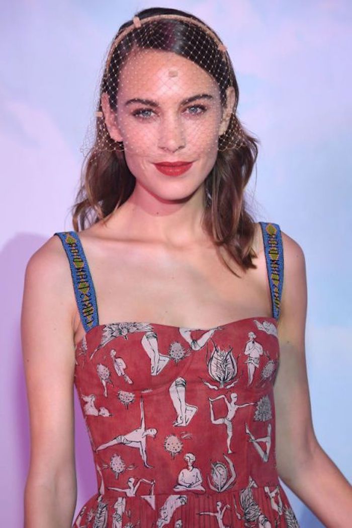 mesh veil worn by alexa chung, in a red dress, with blue straps, and white and black pattern, medium length hairstyles for thin hair, slick side part and wavy ends