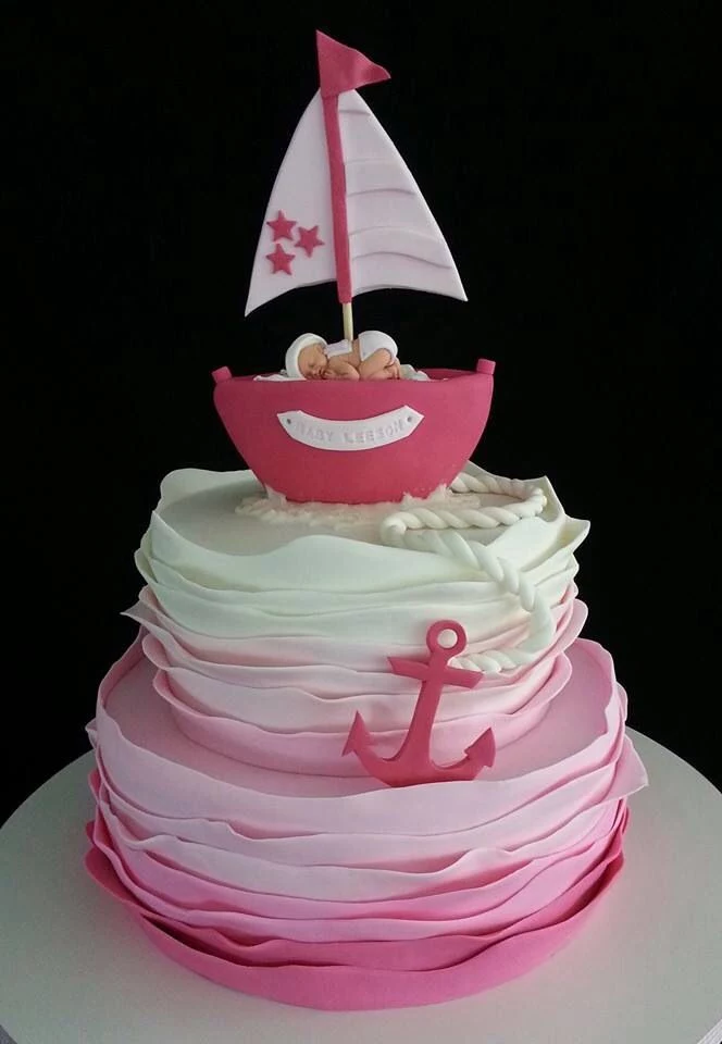 ombre-effect layered cake, in white and four shades of pink, decorated with a pink boat, and containing a realistic baby figurine, baby shower cake toppers girl, pink anchor and white rope, made from fondant