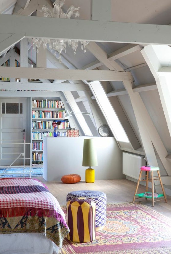 ornamental multicolored rug, inside an attic room, with light laminate floor, white ceiling beams, room design, bed with multicolored cover, and book shelves