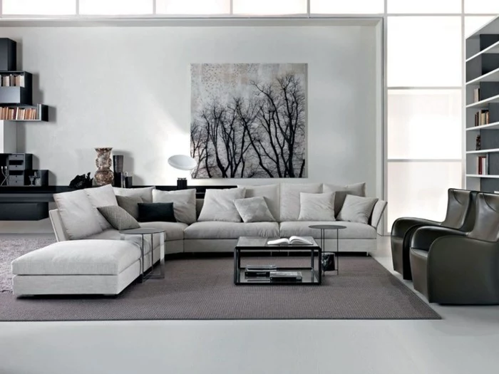 large pale grey corner sofa, and a black coffee table, inside a spacious room, with white walls, how to decorate a living room, two black leather armchairs
