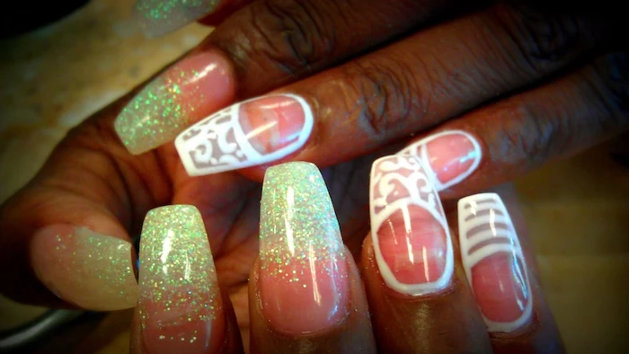 hand-drawn details in white, and pale blue glitter, decorating the nails of a coffin-shaped manicure, painted in a neon pink nail polish