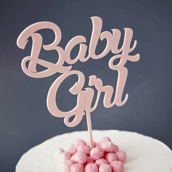 baby shower cake toppers girl, close up of a pale pink cake topper, reading baby girl, placed on a white cake, with pink decorations