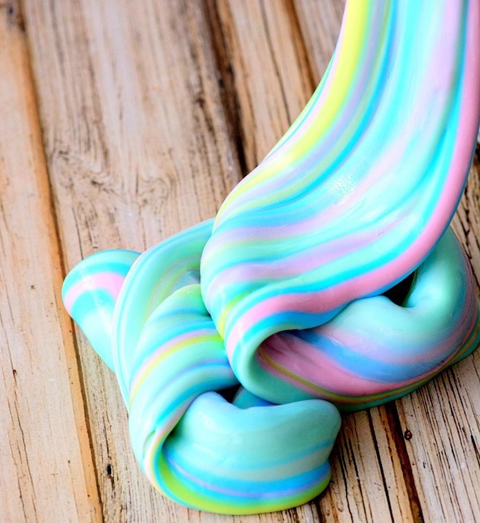 pastel rainbow colored twisted goo, with turquoise and blue, yellow and green, pink and purple stripes, on a wooden surface, how to make slime with borax