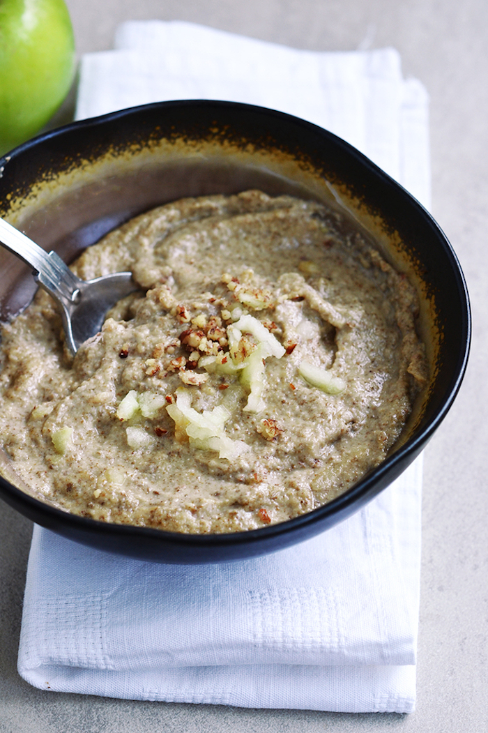 grated green apple, cinnamon and crushed nuts, topping a black bowl, of creamy beige porridge, placed on a folded white napkin, best breakfast for weight loss