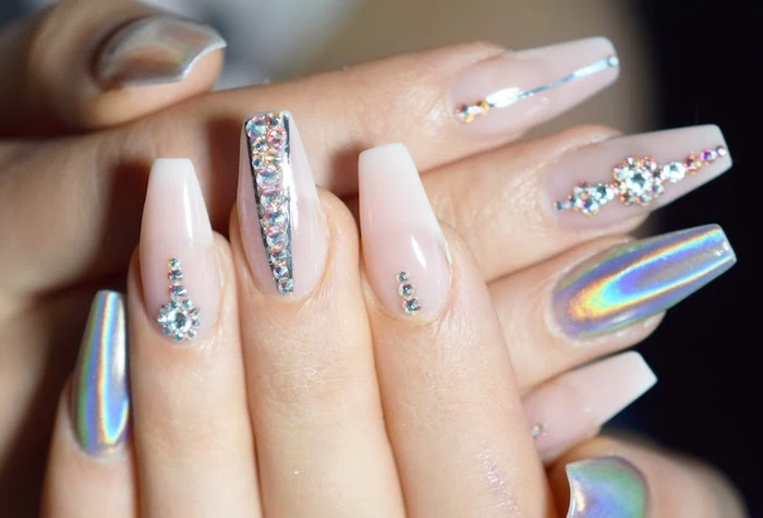 hologram-effect nail polish, on four fingers, the other six are painted in a very pale, baby pink color, and decorated with rhinestones, coffin nail designs