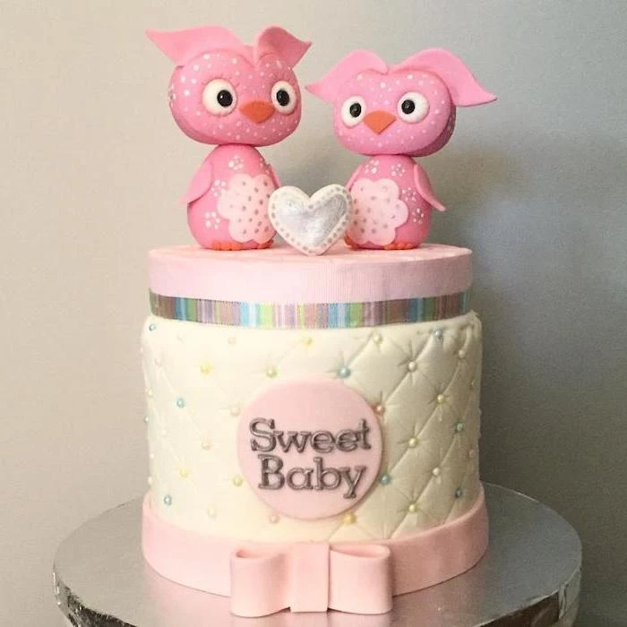 pair of pink owl figurines, placed near a small, white and silver heart, baby shower cake toppers girl, on top of a cream and pink cake, decorated with multicolored pearls, and the words sweet baby
