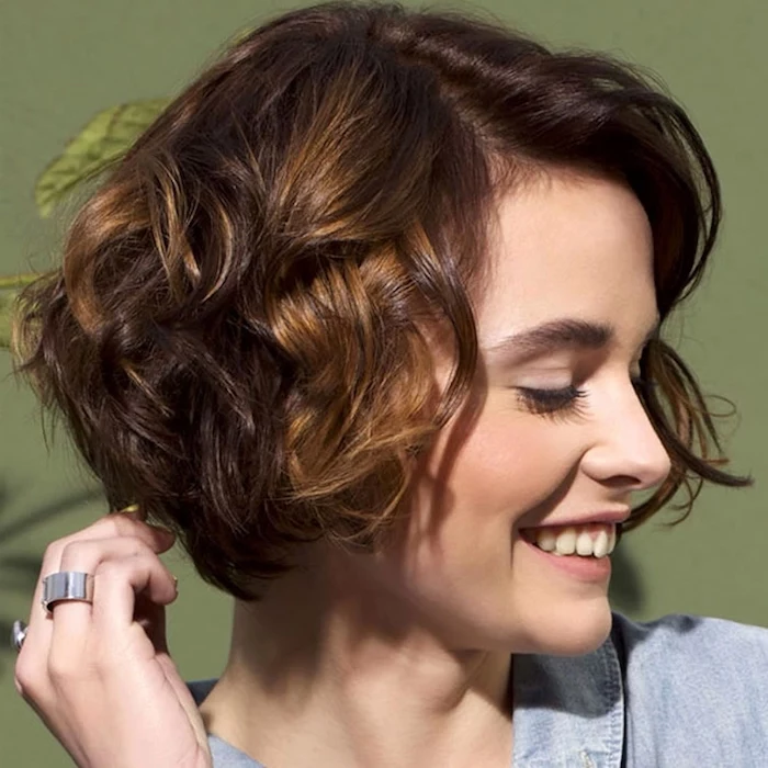 smiling young woman, head turned to one side, wearing a curled bob, with deep side part, short hairstyles for fine hair, in brunette and dark blonde tones