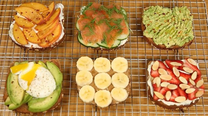 six different kinds of toppings, on pieces of toast, placed on a metal griddle, simple breakfast ideas, peaches and creamed cheese, salmon and cucumber, peanut butter and banana