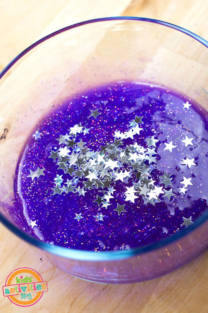 star shapes in metallic silver, poured over a gooey purple mixture, with pink adn silver glitter, inside a clear glass bowl