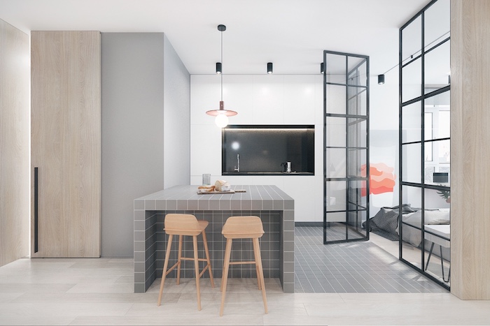 minimalistic kitchen in neutral colors, creamy grey kitchen island, two beige stools, sink with black backsplash, open veranda door