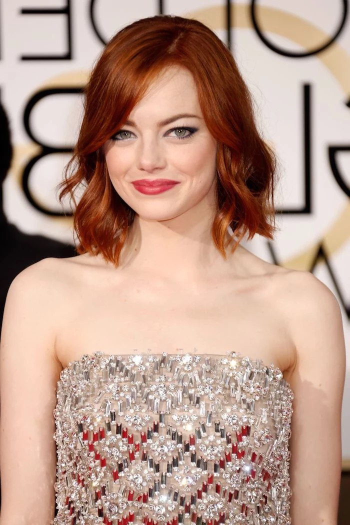 fiery red or ginger hair, shaped in a long bob, with side bangs and waves, short hairstyles for fine hair, on emma stone, smiling in a sequined silver dress