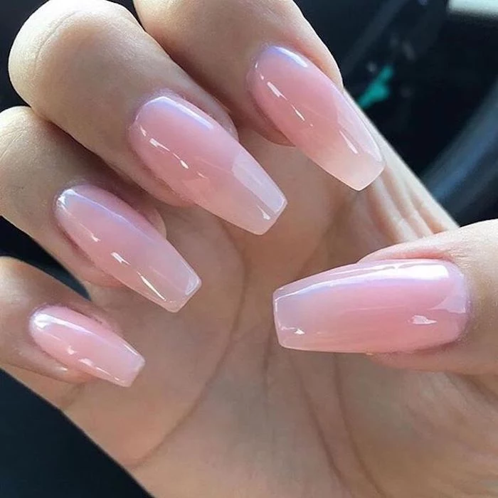 close up of a hand, with folded fingers, long coffin-shaped manicure, painted in a pale, pastel pink nail polish