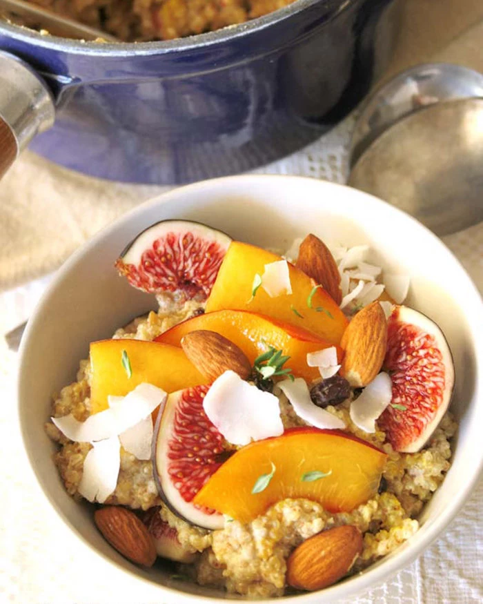flakes of coconut and almonds, peach and fig slices, topping a bowl of porridge, low calorie breakfast, blue pan with more porridge 