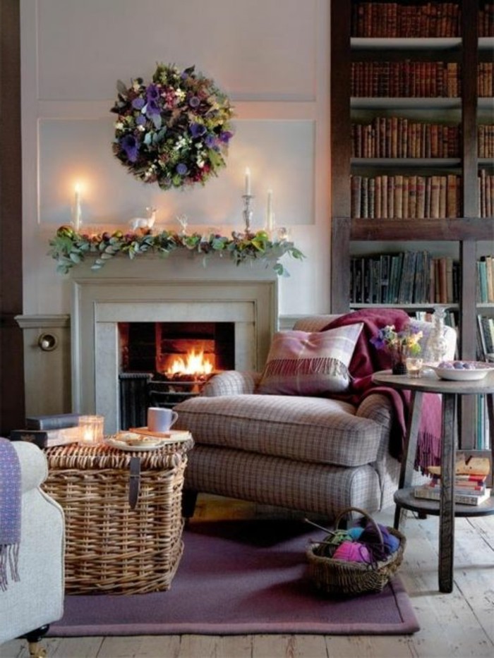 lit fire inside a fireplace, wicker coffee table, and retro armchair, home decor inspiration, dark brown bookshelves, candles and flower decorations 