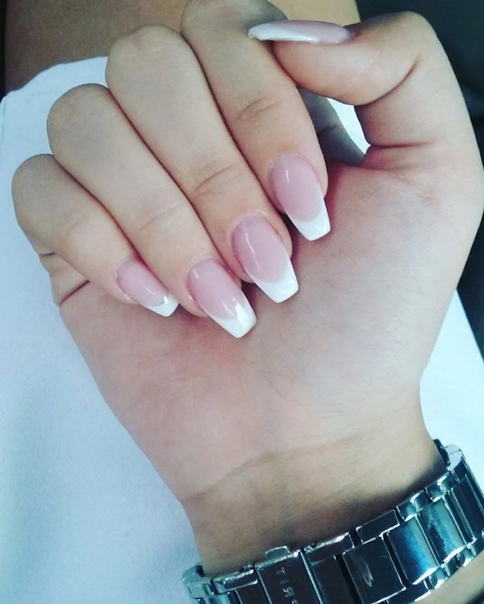 square tips on medium long, oval nails with french-style manicure, pale pink base, and white tips, on a hand with folded fingers