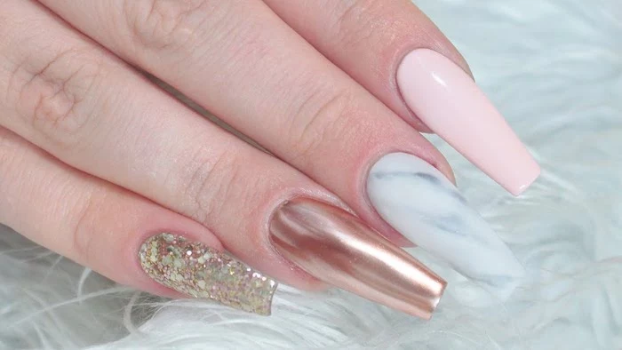 different kinds of nail polish, on four coffin shaped nails, iridescent glitter and rose gold metallic effect, marble-style and plain pastel pink