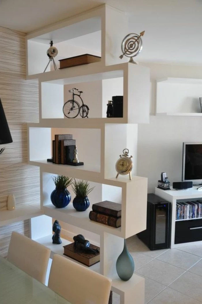 shelves in white, containing books and vases, and various decorative items, how to decorate a living room, tv on a white and black stand, in the background