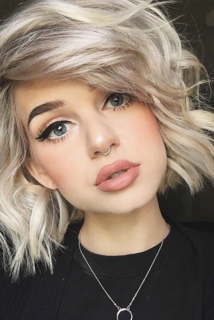 short sassy haircuts, curled platinum bob, with side bangs, on girl with bold black eyeliner, and matte lipstick in nude beige