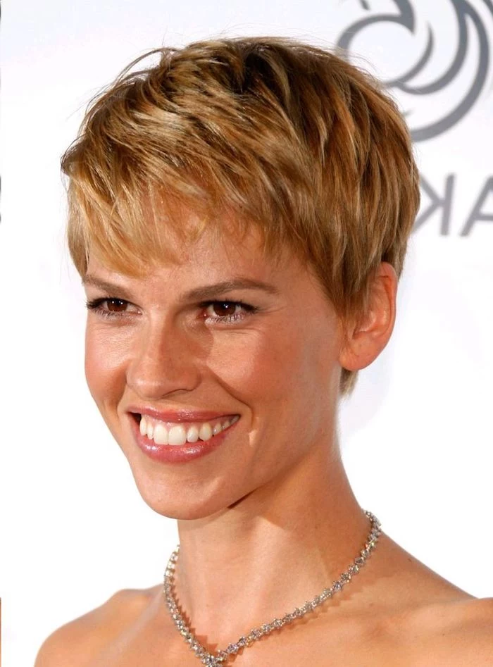 short textured pixie cut, on brunette hair with honey blonde highlights, short haircuts for thin hair, worn by smiling hilary swank