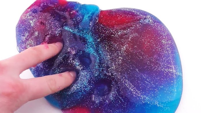 poking holes into a pile slimy goop, in red and blue, purple and pink, decorated with fine glitter, how to make slime with borax, pure white surface