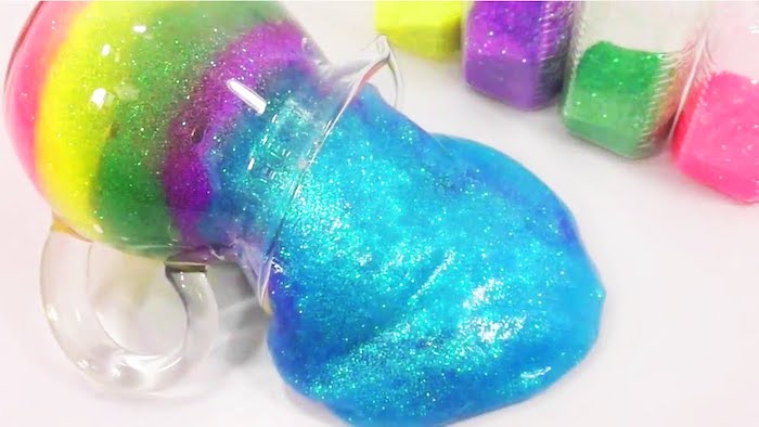shimmering goop in five different colors, turquoise and purple, green and yellow and pink, how to make slime with borax, spilling from a glass jug