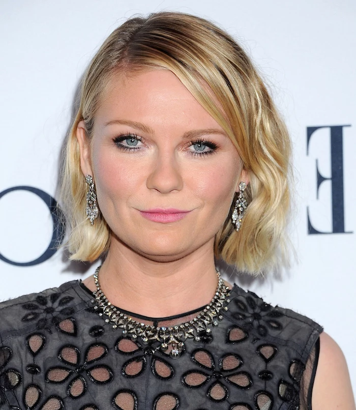 pewter grey top, with flower-shaped cutouts, worn by kirsten dunst, with short slightly wavy bob, side part and dark blonde roots, short haircuts for fine hair